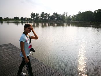 Woman standing by lake against sky