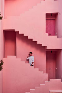 Young latin man talks on his mobile in a pink building