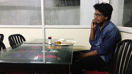 Young man looking away while sitting on table at restaurant