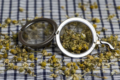 Close-up of dried flowers with strainer on tablecloth