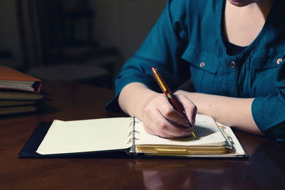 Midsection of woman reading book while sitting on table