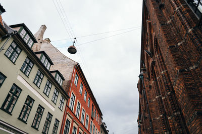 Low angle view of buildings in city against cloudy sky