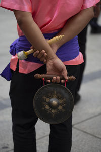 Midsection of man holding musical instrument while standing on footpath