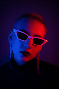 Portrait of woman wearing sunglasses against black background
