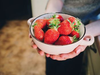 Cropped hand of person holding bowl of strawberries