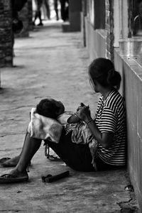 Rear view of mother and daughter sitting on floor