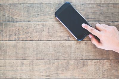 Low section of person using mobile phone on table