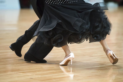 Low section of couple dancing on hardwood floor