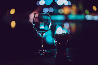 Close-up of empty wineglass on table against illuminated lights