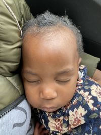 Close-up of cute baby relaxing by mother