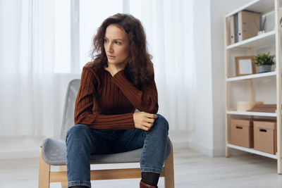 Young woman sitting on sofa at home