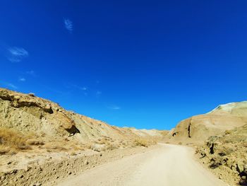 Road amidst desert against blue sky