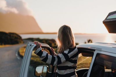 Rear view of woman using mobile phone against sky