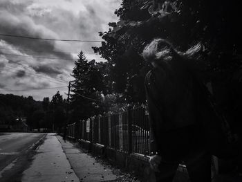 Woman on road amidst trees against sky