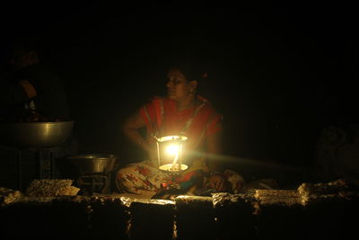Midsection of man holding illuminated candles