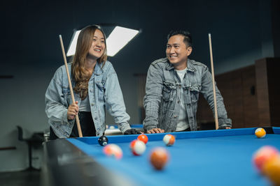 Portrait of young woman playing pool