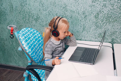 Girl using laptop while sitting on table