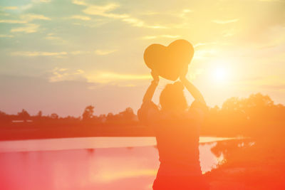 Silhouette woman standing against orange sky during sunset