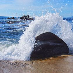 Waves splashing on sea against sky