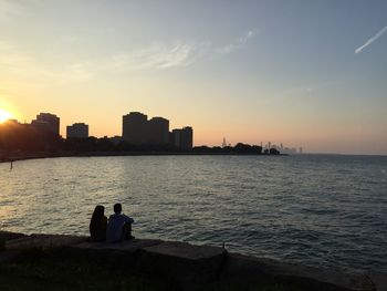 Silhouette of people in front of sea during sunset