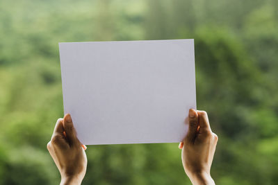 Close-up of hand holding paper against blurred background