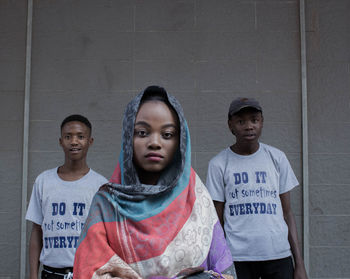 Portrait of two people standing against wall