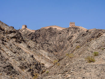 Low angle view of rocky mountains against clear blue sky