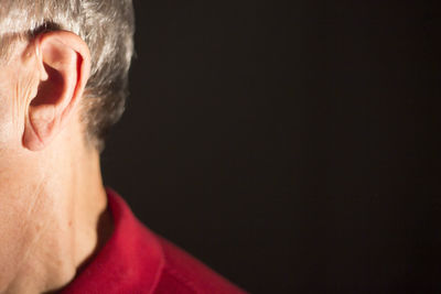 Close-up of man with hearing aid on black background