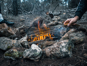 Low angle view of man relaxing on barbecue grill in forest