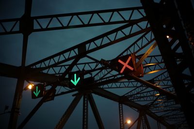 Low angle view of illuminated road signals against sky at night