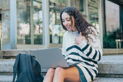 Young woman using laptop while sitting on staircase