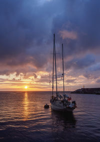 Sailboats sailing on sea against sky during sunset