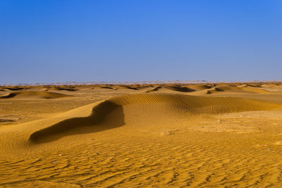 Scenic view of desert against clear blue sky