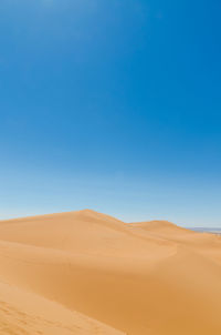 Scenic view of desert against clear blue sky