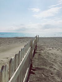 Wooden posts on beach against sky