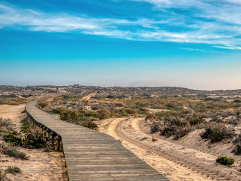 Dirt road passing through landscape against sky