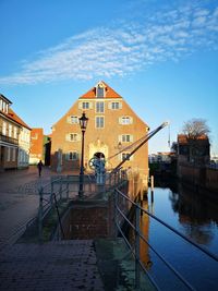 Buildings by canal against sky in city