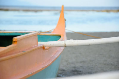 Close-up of boat moored on beach against sky