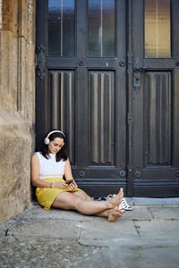 Young woman sitting on closed door