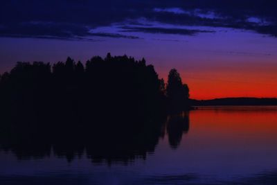 Silhouette trees by lake against sky at sunset