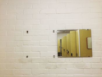 Reflection of cabinet in mirror at brick wall