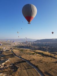 Hot air balloon flying over landscape against clear sky