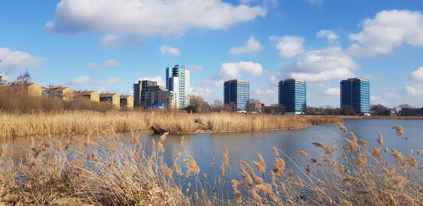 Buildings by lake against sky