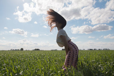 Portrait of beautiful woman shaking hair in green field