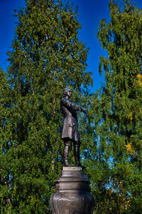 Low angle view of statue in park against clear blue sky