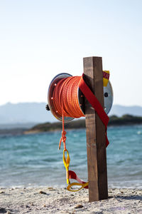 Close-up of red umbrella on beach against clear sky