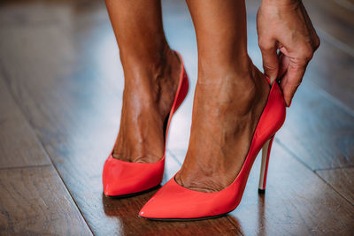 Woman putting on red high heeled shoes.