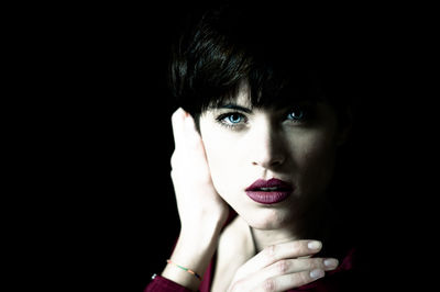 Close-up portrait of young woman against black background