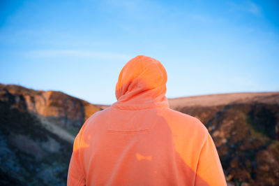 Rear view of man against orange sky