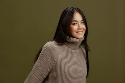 Portrait of young woman standing against wall